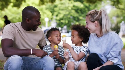 Multiracial family on walk in public park eating ice cream. - Powered by Adobe