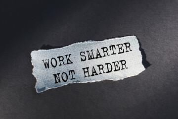 Work Smarter Not Harder text on torn paper on a dark table in sunlight.