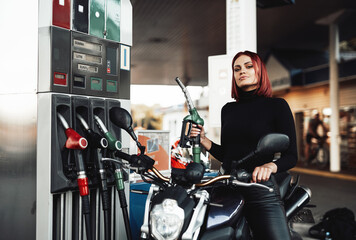 Obraz na płótnie Canvas Positive girl sitting on her expensive urban bike. Custom sport motorcycle and its female owner. Vintage photo of refueling.