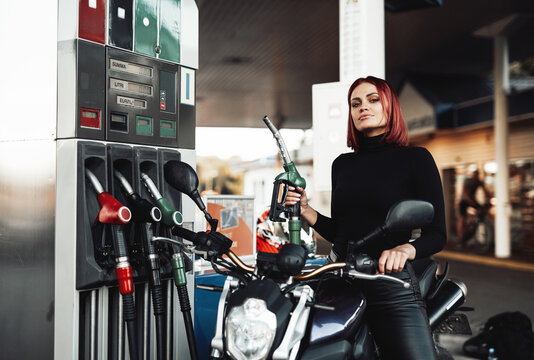 Positive girl sitting on her expensive urban bike. Custom sport motorcycle and its female owner. Vintage photo of refueling.
