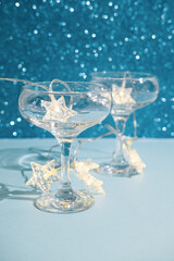 Christmas minimal festive background with star garland in glasses of champagne. Abstract Christmas and New Year color glitter background shiny blue ai aqua. Bright sparkling wallpaper bokeh texture.
