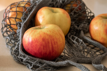 Fresh apples in a string bag on a table