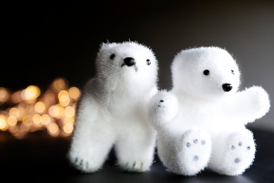 Two Polar Bear Toys And Some Lights Against Black Background