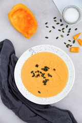 Pumpkin carrot cream soup on white marble background, top view