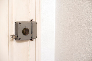 Una cerradura gris de una puerta blanca con una pared blanca