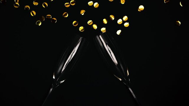 Glasses for champane with blown away konfetti on a black background