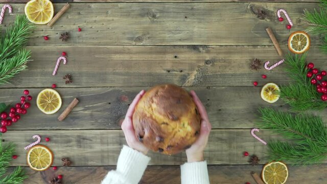 Placement of panettone on wooden table with Christmas decoration.
