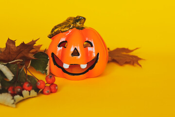 Yellow background with halloween pumpkin and dry autumn leaves