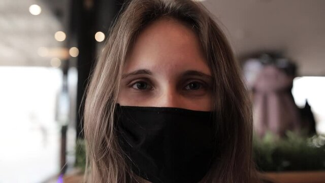 A girl in a protective mask is sitting in a cafe. Close up