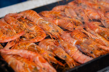 Close up: process of cooking fresh red langoustine shrimps, prawns on grill at summer local food market. Outdoor cooking, barbecue, gastronomy, seafood, cookery, street food concept