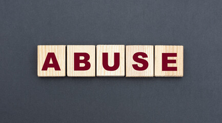 concept word ABUSE on wooden cubes on a gray background