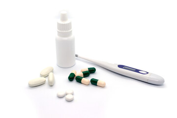 Medical electronic thermometer, medicine, drops and pills on white background