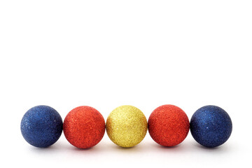 Five Christmas baubles blue, red and yellow color in row on a white background. Selective focus, copy space.