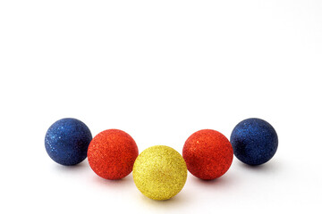Five Christmas baubles blue, red and yellow color on white background. Selective focus, copy space.
