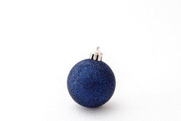 One blue shiny Christmas ball on a white background. Selective focus, copy space.