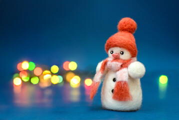Toy wool snowman on a blue background with bokeh