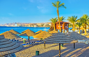 The morning beach with straw sunshades, Eilat, Israel