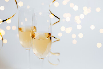 Two glasses of champagne with lights and ribbons on a white background holiday