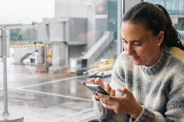 woman waiting at the airport using her smartphone