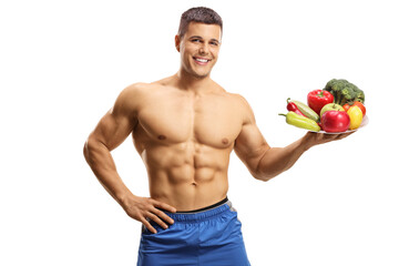 Naklejka premium Topless muscular man holding a plate of fruits and vegetables