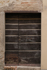old brick wall with damaged and weathered wooden door, closed and blank shutters with space for text, perfect background