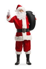 Full length portrait of santa claus holding a car tire and showing thumbs up