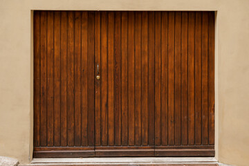 Wooden folding garage door with closed shutter, bright beige wall, space for text on the blank shutter, perfect background for a gift card