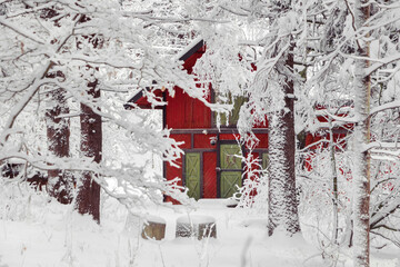 Beautiful red wooden house in snow fairy forest Sweden. House painted in traditional Swedish color. Winter scenery with red cottage surrounded by trees covered with snow and frost. Space for your text
