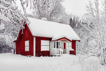 Beautiful red wooden house in snow fairy forest Sweden. House painted in traditional Swedish color. Winter scenery with red cottage surrounded by trees covered with snow and frost. Space for your text - Powered by Adobe