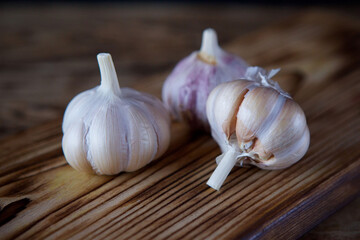 Garlic lies on a wooden chopping Board.