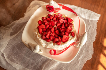 Pavlova cake with strawberries stands on a beautiful tortilla in the morning sun