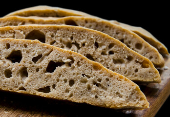 Homemade sliced ciabatta bread on black background closeup.