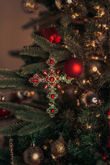 Gold and red cross ornament hanging on a Christmas tree branch