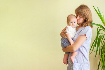 Young woman in white with a infant baby in her arms is looking at her child