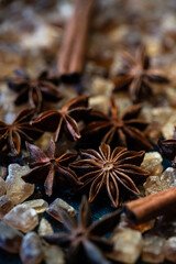 Close up anise stars , brown sugar crystals, and cinnamon sticks on deep blue background.