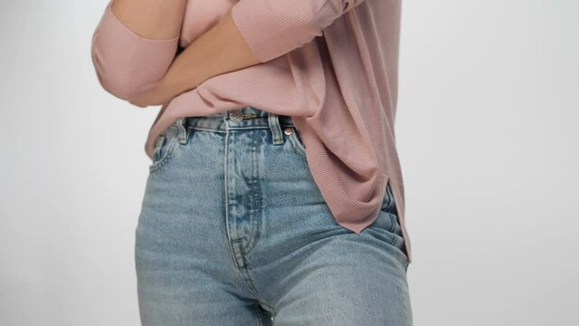hips and hands of a young woman in jeans on a white background