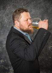 Solid bearded man in suit tasting whisky in a glass