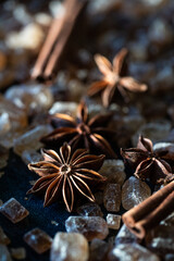 Close up anise stars , brown sugar crystals, and cinnamon sticks on deep blue background.