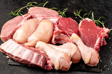 Various types of raw meat of beef, pork, chicken on a stone background	