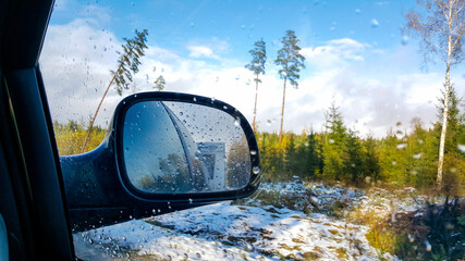 Car campin travel trip active vacation on sunny winter day, indoor view from car to front side window to outdoor back view mirror caravan trailer reflection. Car traveling and winter holidays concept.
