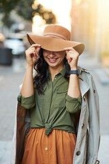 Playful beauty. Young happy caucasian woman adjusting hat and smiling while standing on the city street, enjoying walking on warm autumn day