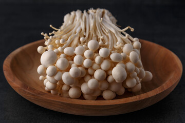 Enoki mushrooms over black background .Enokitake or enoki (Flammulina velutipes) white mushroom used i food and salads, also known by the name golden needle mushroom or lily mushroom.