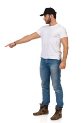 Naklejka premium Young Casual Man Wearing Black Cap Is Looking Away And Pointing