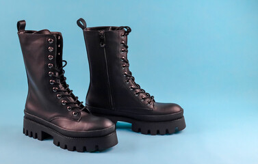 combat boots on blue.
Women's army boots on the left on a blue background with space for text on the right, close-up side view.