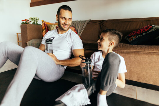 Latin Father And Son Rest After Exercising At Home