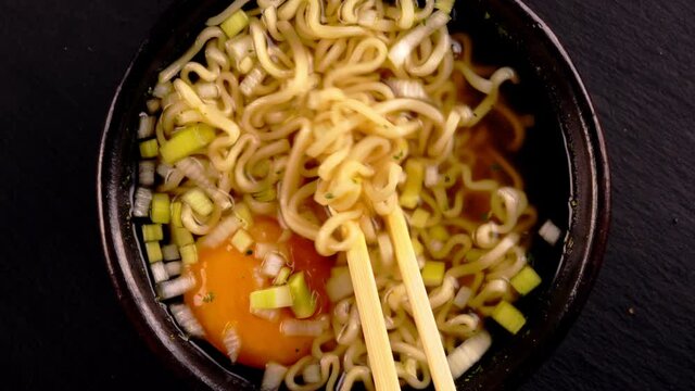 Hand uses chopsticks to pick up chinese noodles.