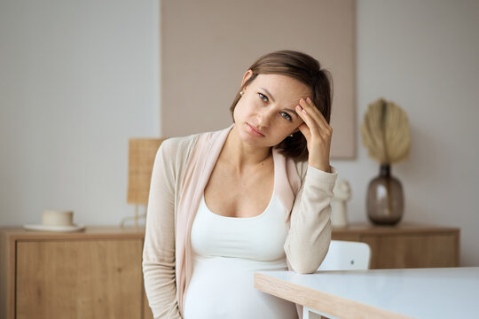 Pregnant woman suffering from headaches while sitting at the table. High quality photo