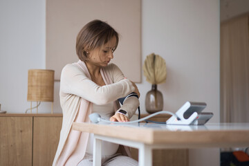 Pregnant woman measures blood pressure with an electronic tonometer. neuralgia during pregnancy, poor health. Hypertension. Severe pregnancy. Headache, migraine. High quality photo