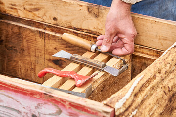 beekeeper tools and his hand on the background of an open hive
