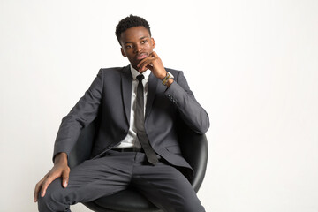 Fototapeta premium handsome young african man in suit on white background in armchair